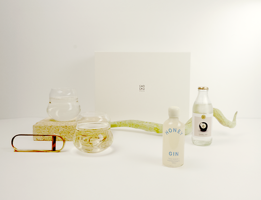 Bottle of Honey Gin with two glasses on a white surface