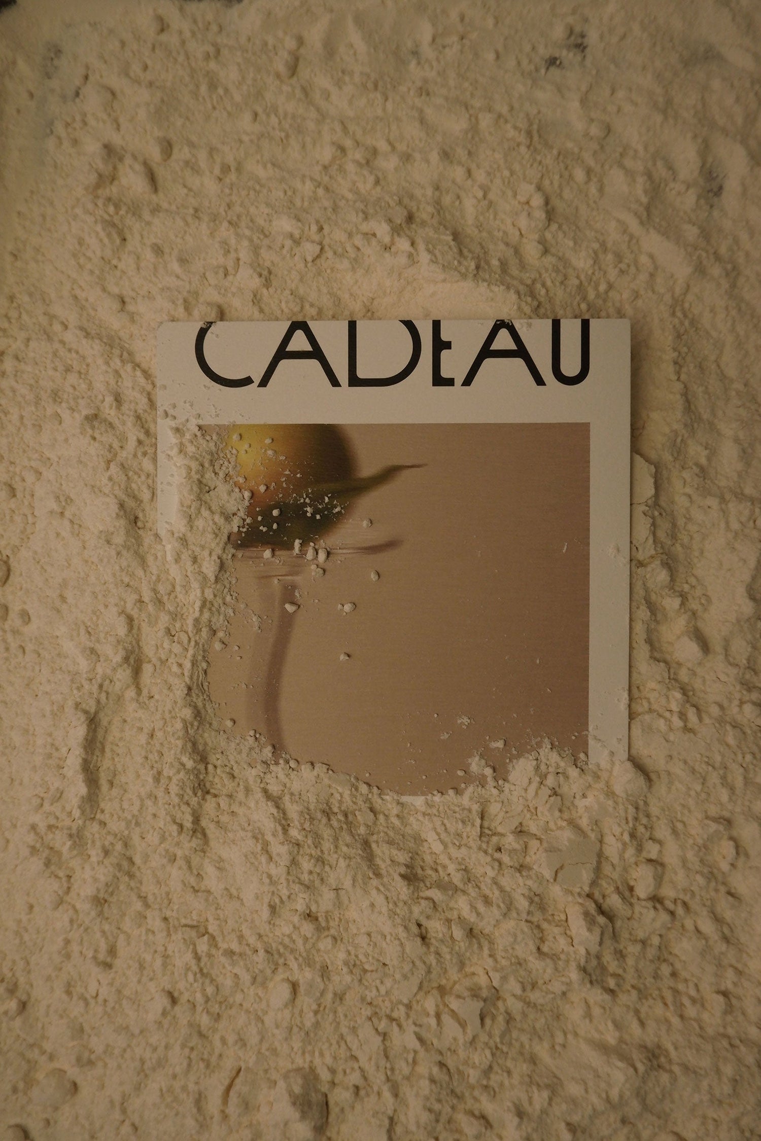 Product packaging with 'Cadeau' branding on a textured beige background