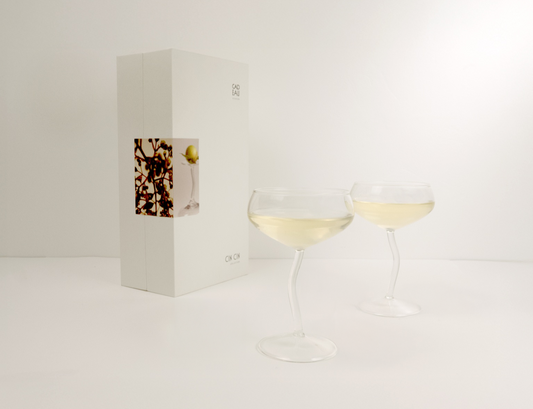 Two wine glasses with white wine next to a wine box on a light gray background