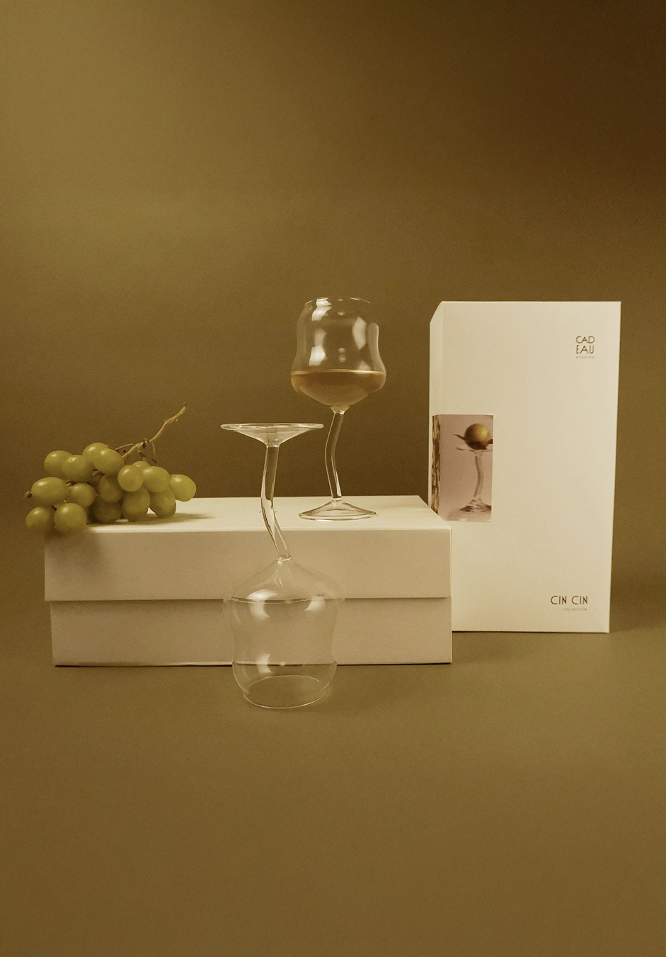 Wine glasses, grapes, and a box on a green background