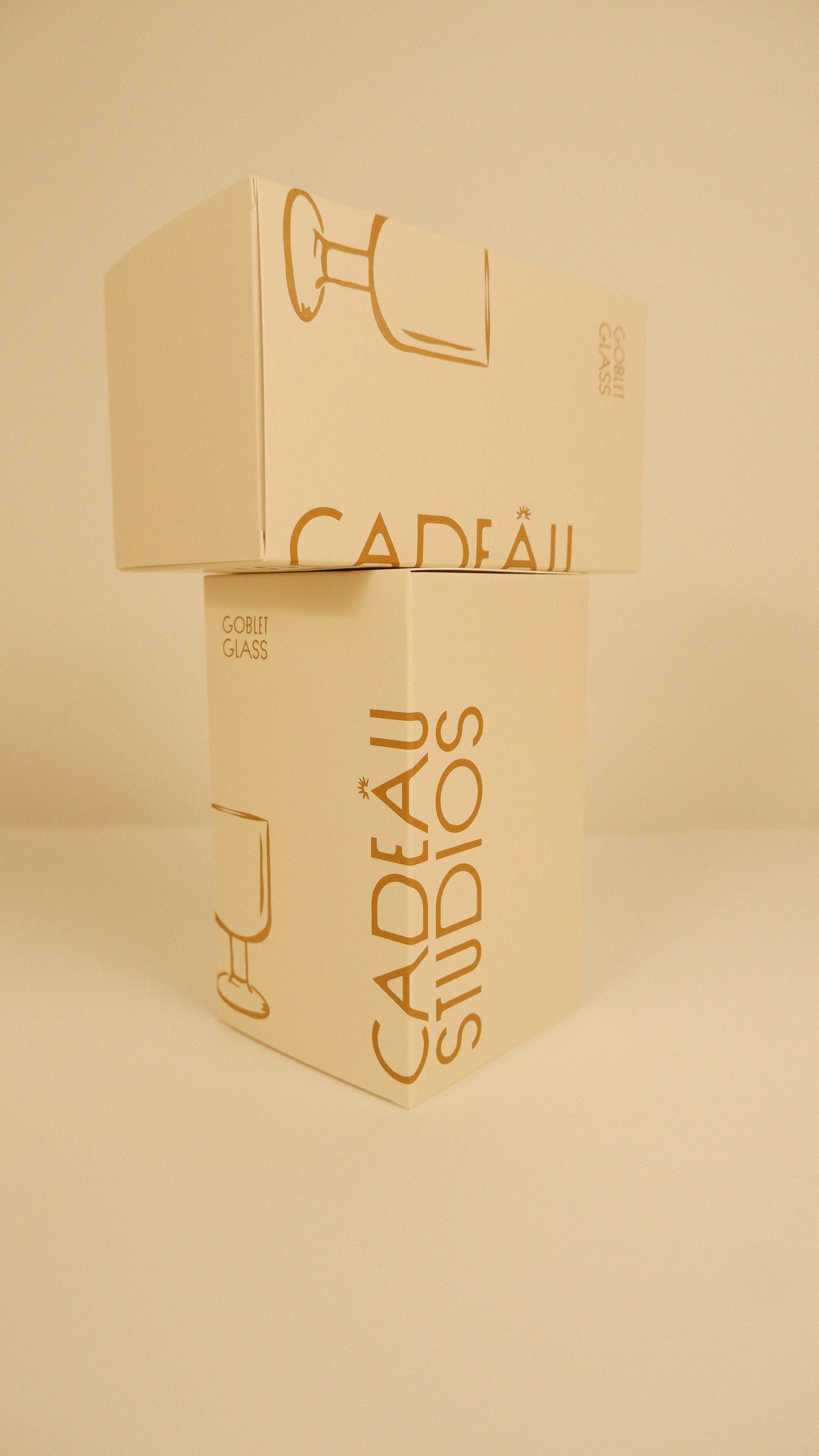 Gold packaging with 'Cadeau Studios' branding on a beige background