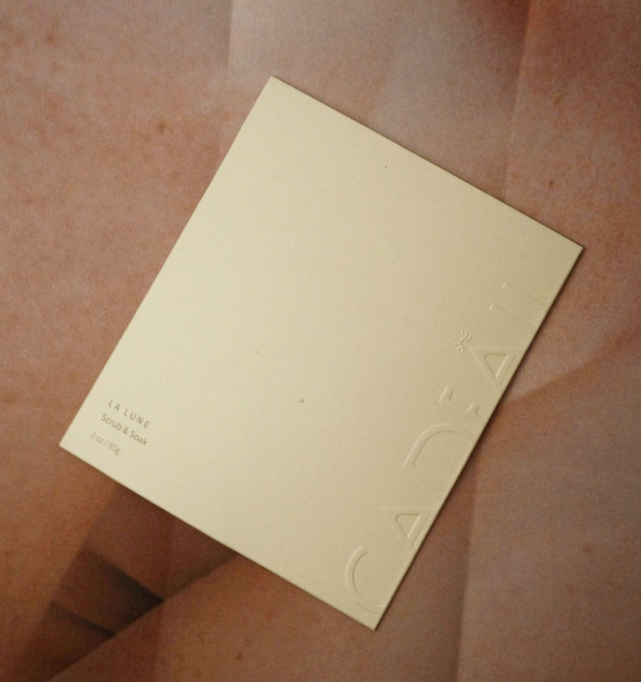 Embossed bath salts packaging placed on a large textured leaf