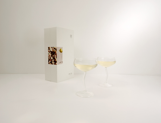 Two wine glasses with white wine next to a wine box on a light gray background