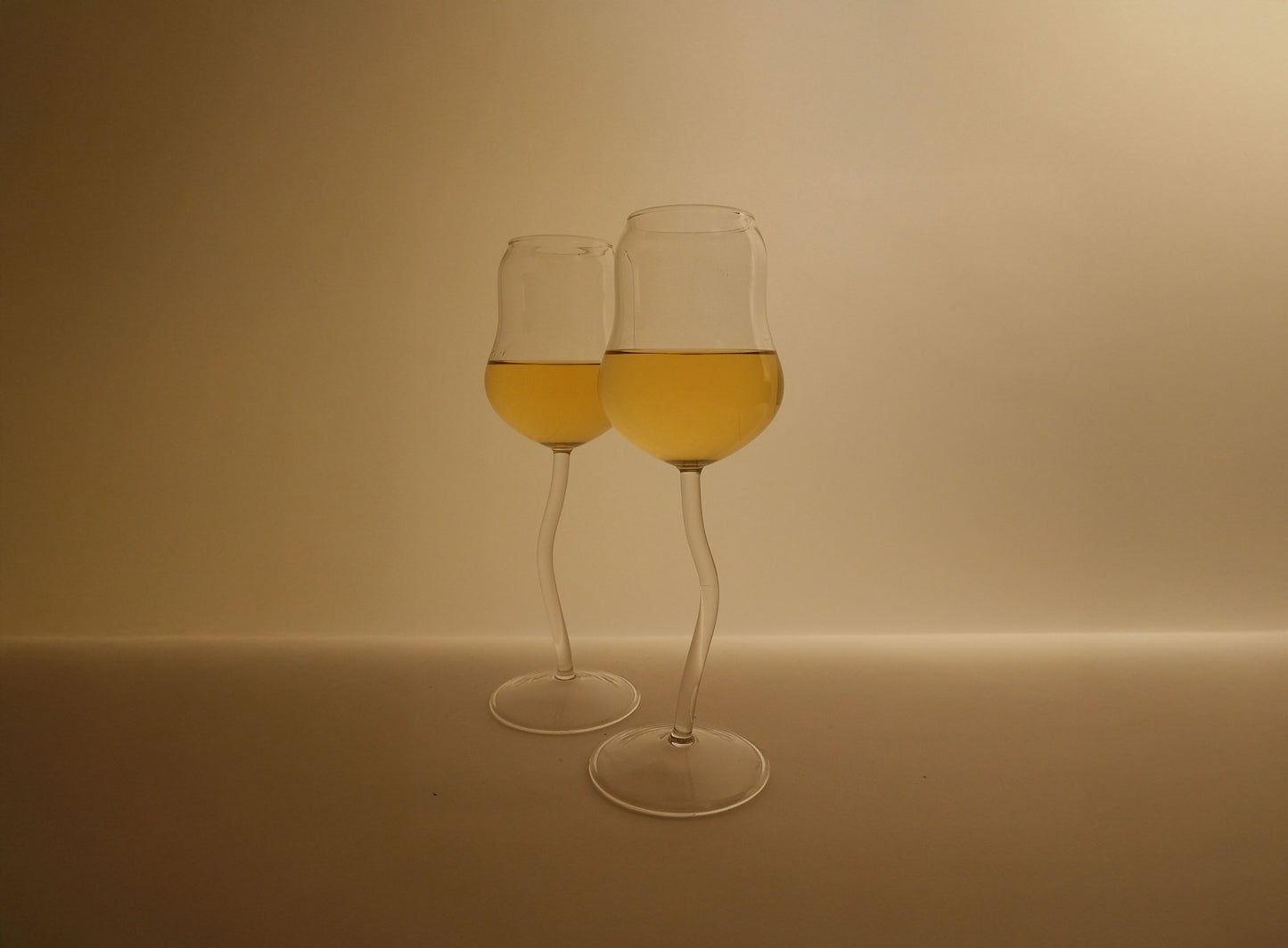 Two glasses of yellow liquid on a beige background