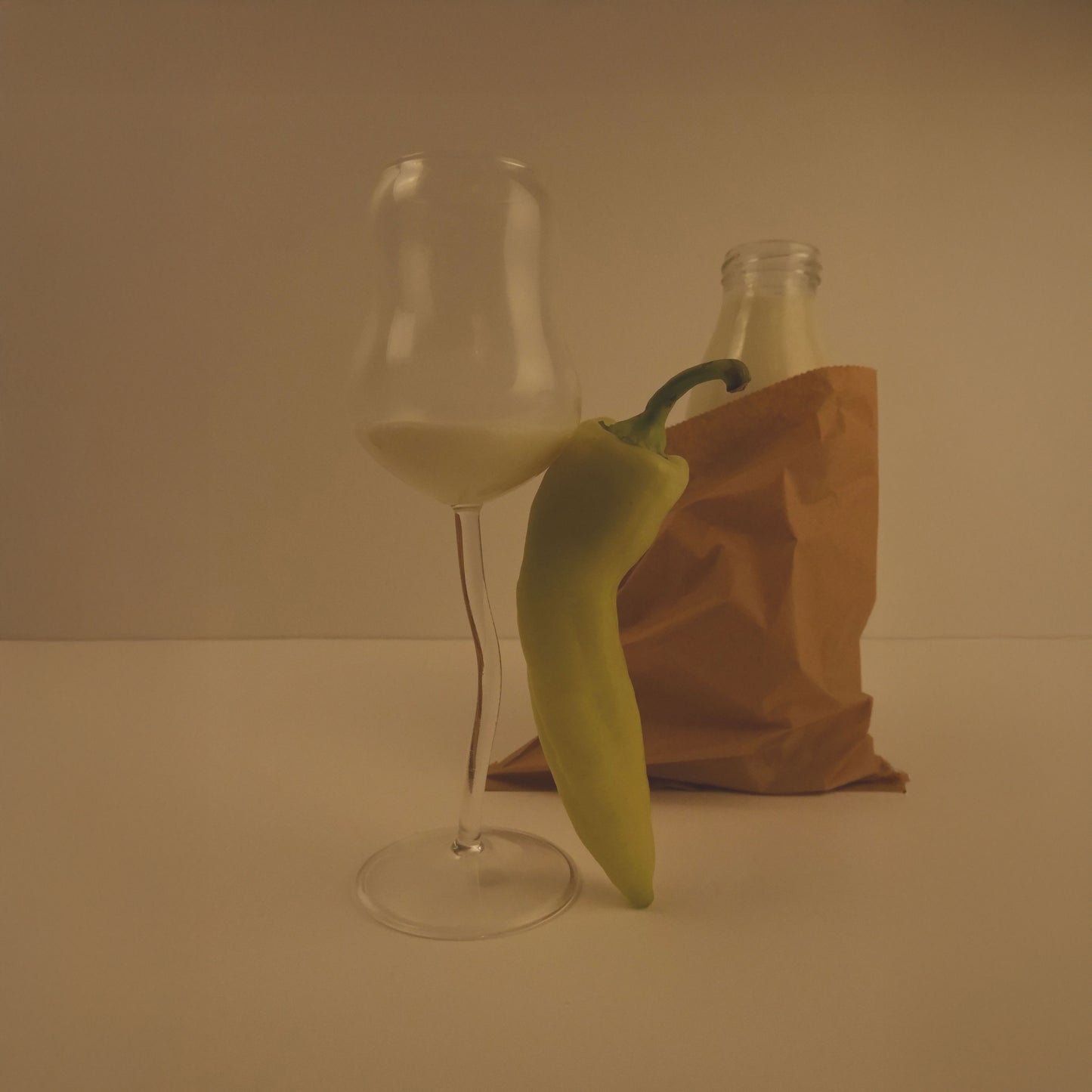 Flute glass with a green pepper on a neutral background