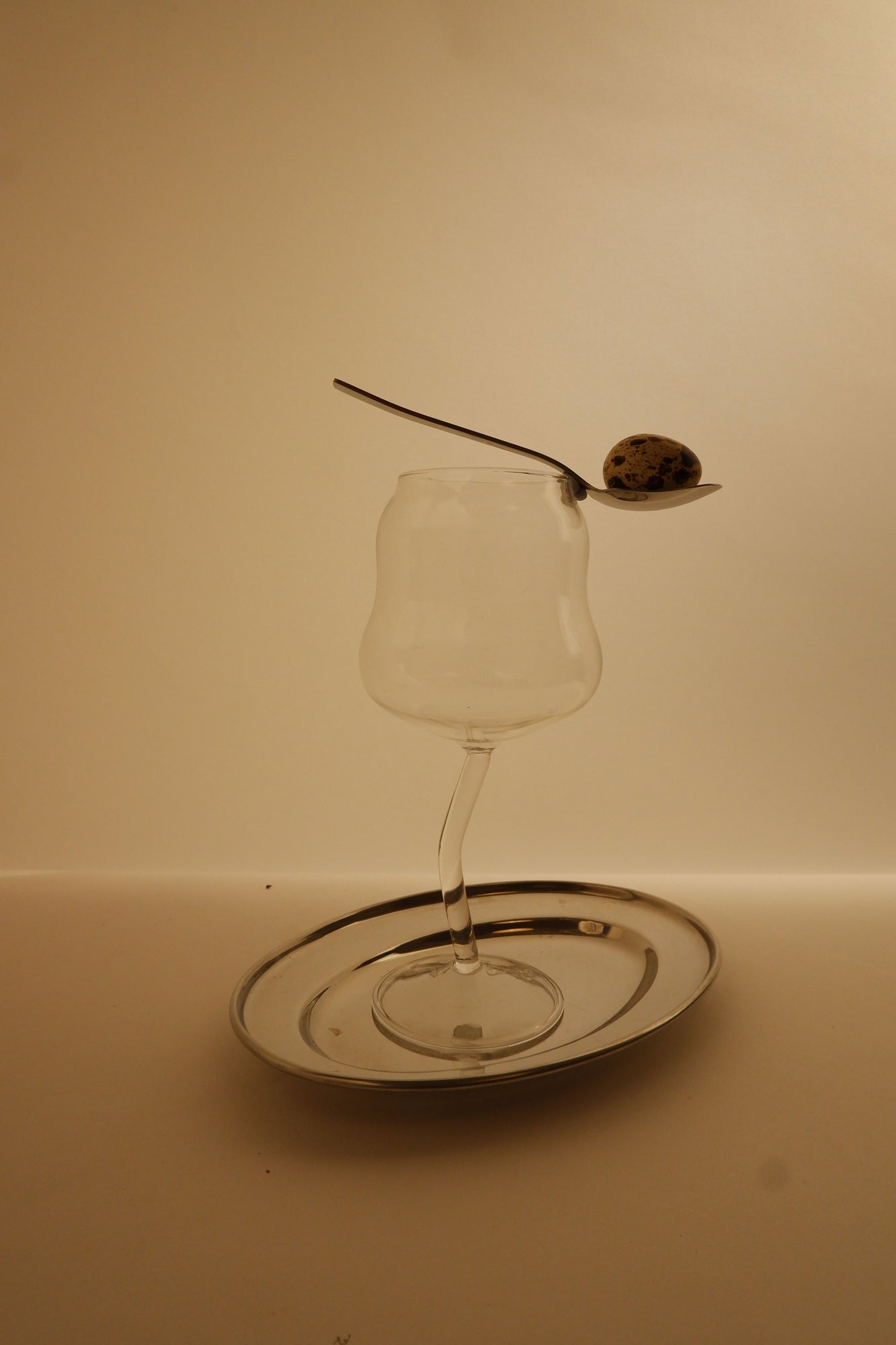 Cin Cin wine glass with a spoon a quail egg on a beige background