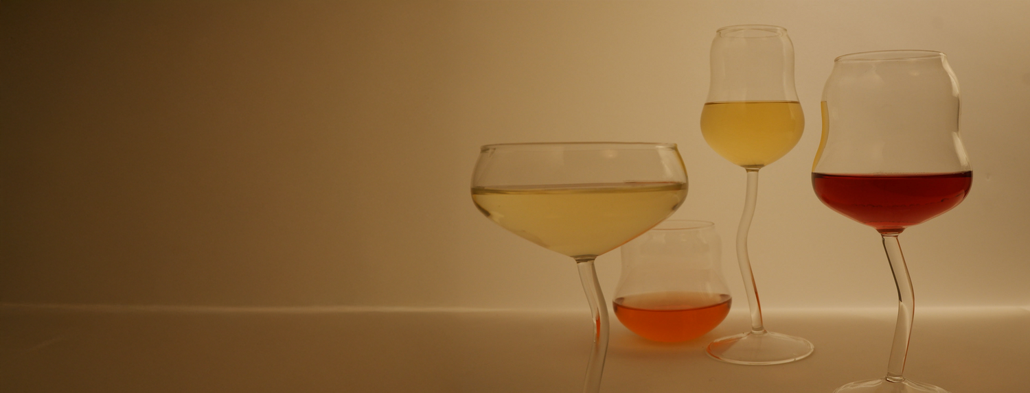 Three wine glasses with different colored liquids on a plain background