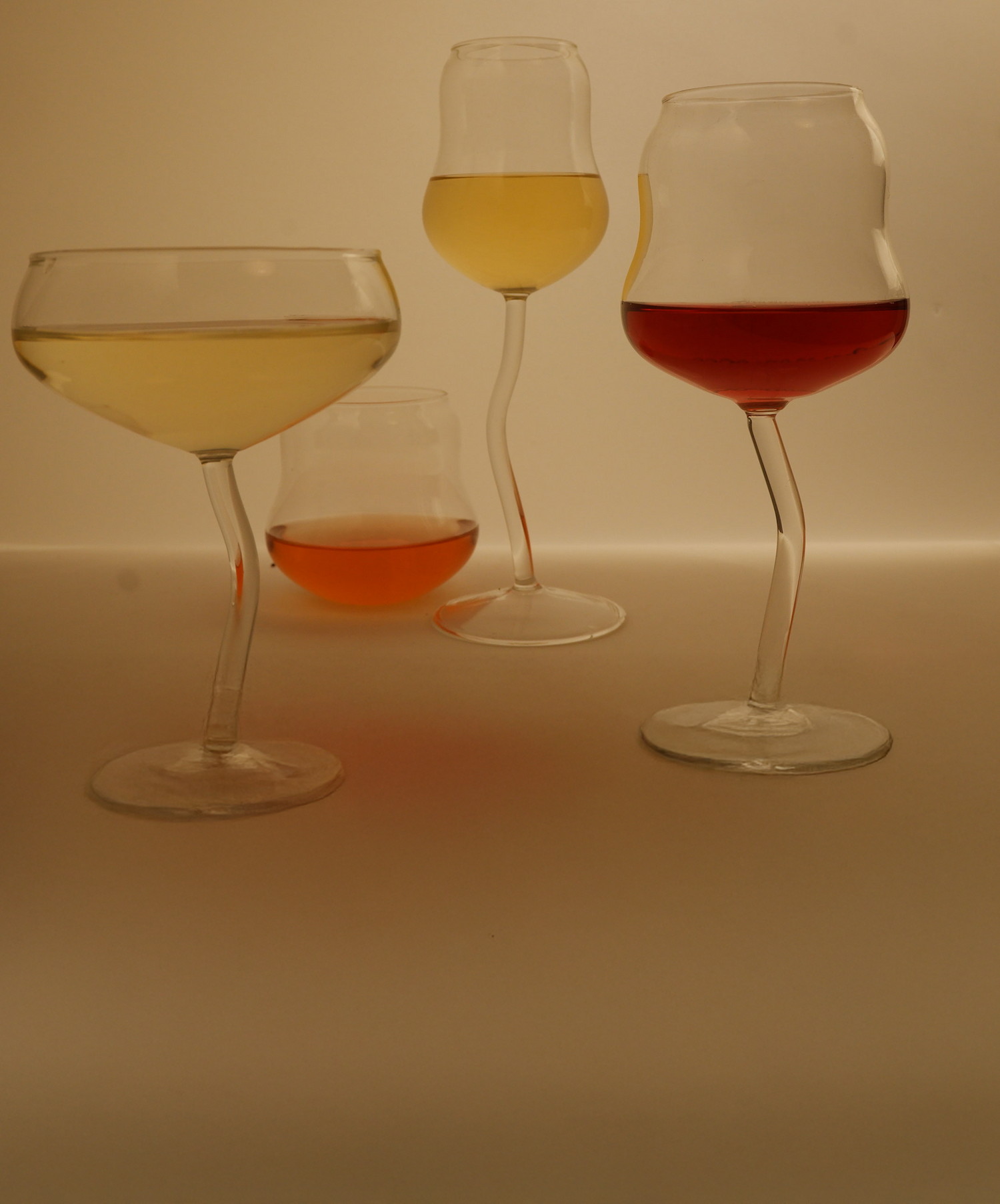 Five wine glasses with different types of wine on a plain background