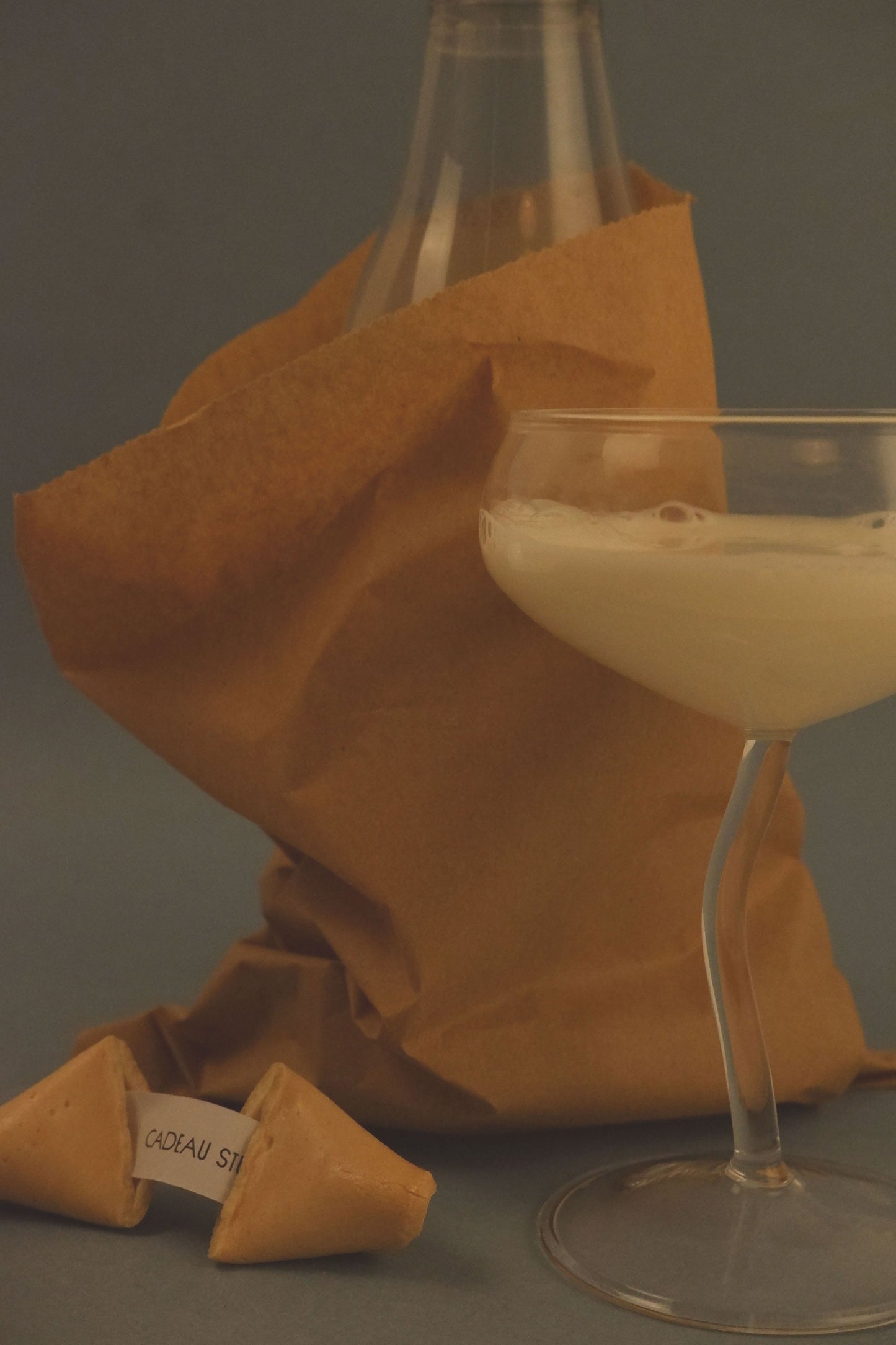 Fortune cookie and glass of white wine on a gray surface