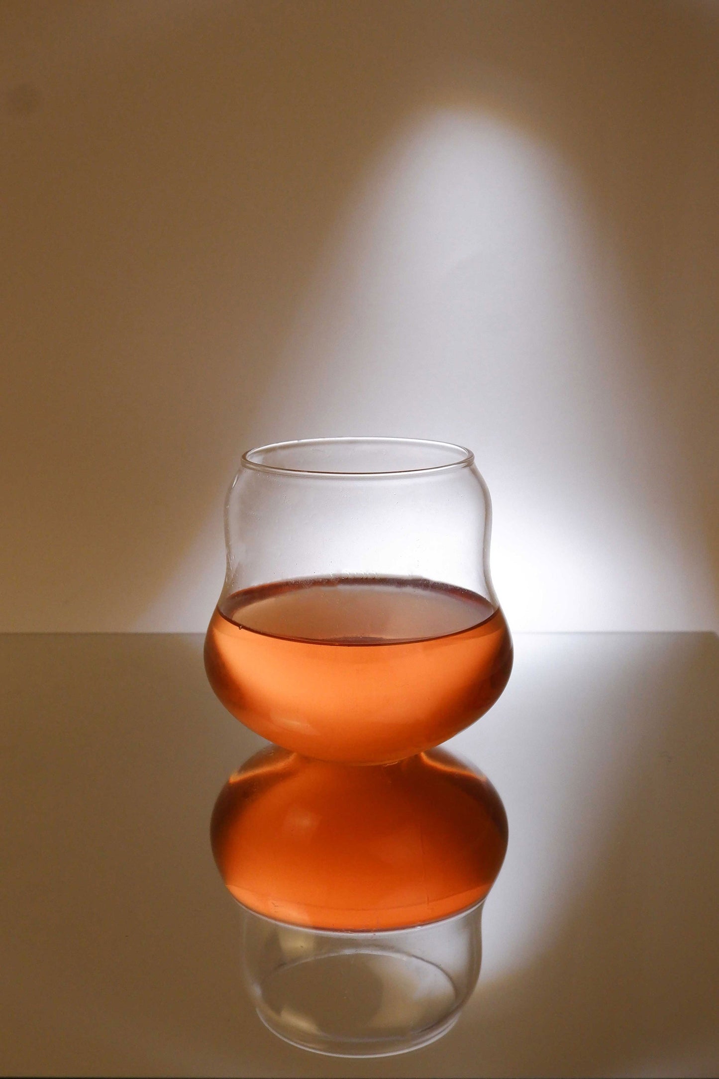 Glass filled with amber liquid on a reflective surface