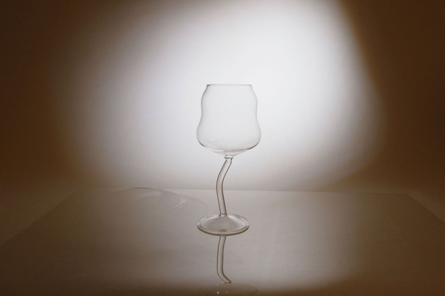 Clear glass wine glass on a reflective surface with a blurred background