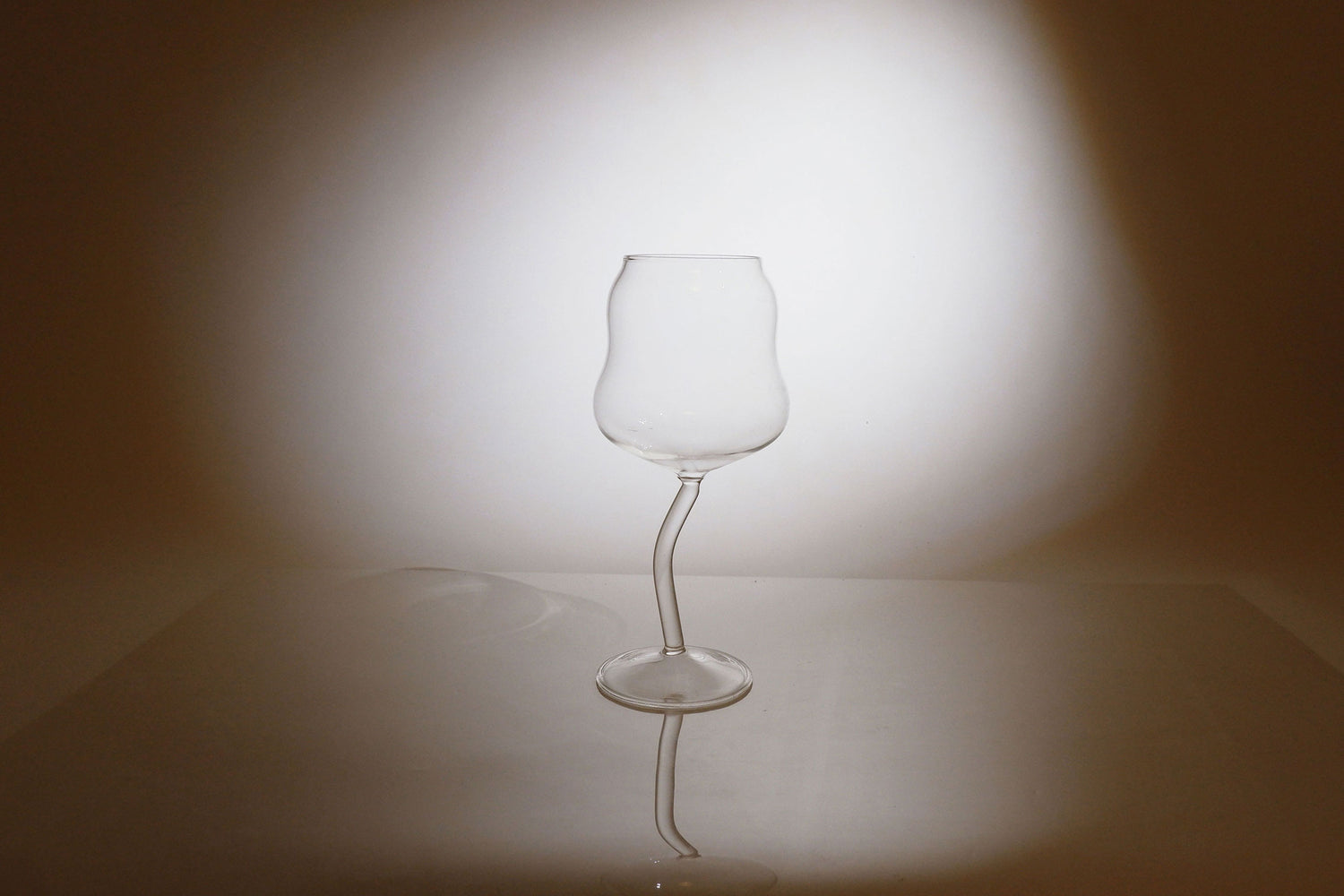 Clear glass wine glass on a reflective surface with a blurred background