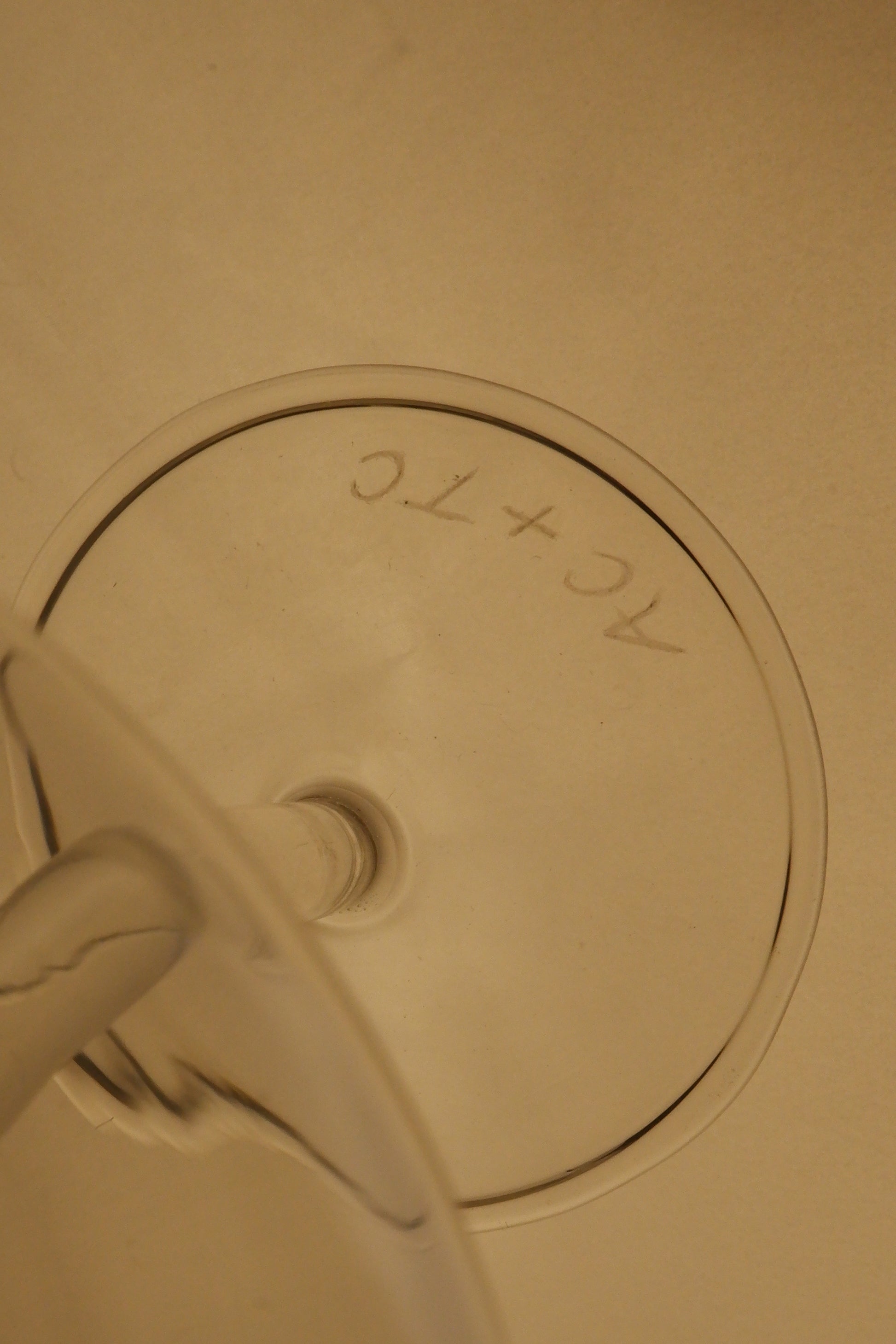 Close-up of a beige ceramic pot with a circular handle and text on a beige background