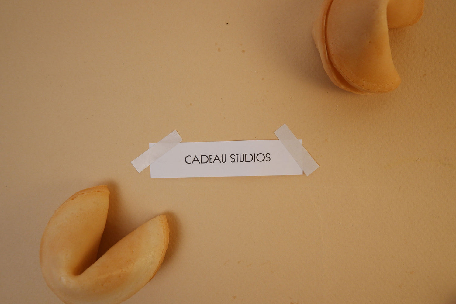 Two fortune cookies on a beige background with a label reading 'Cadeau Studios'.