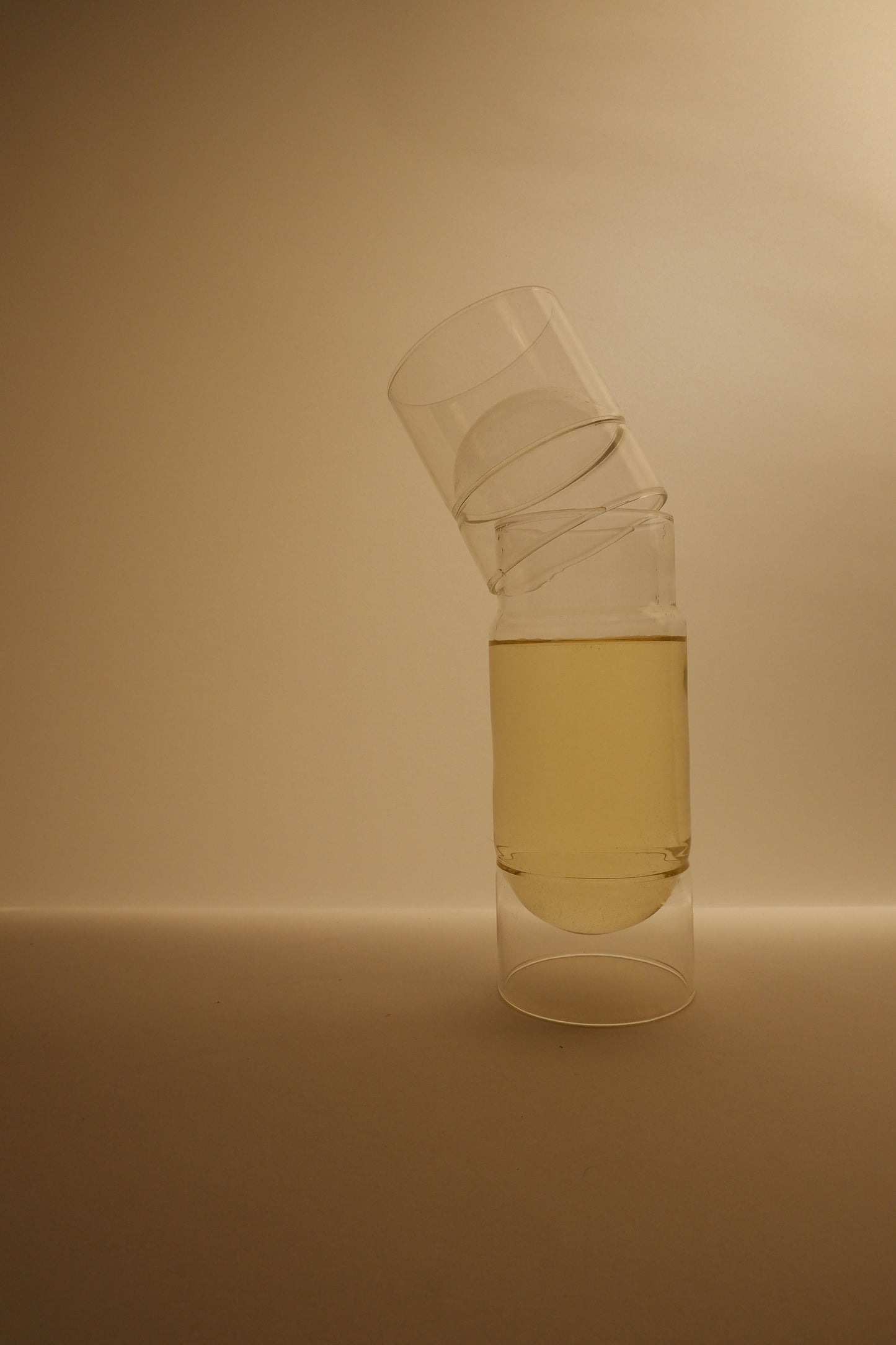 Two glass containers with a liquid inside on a beige background