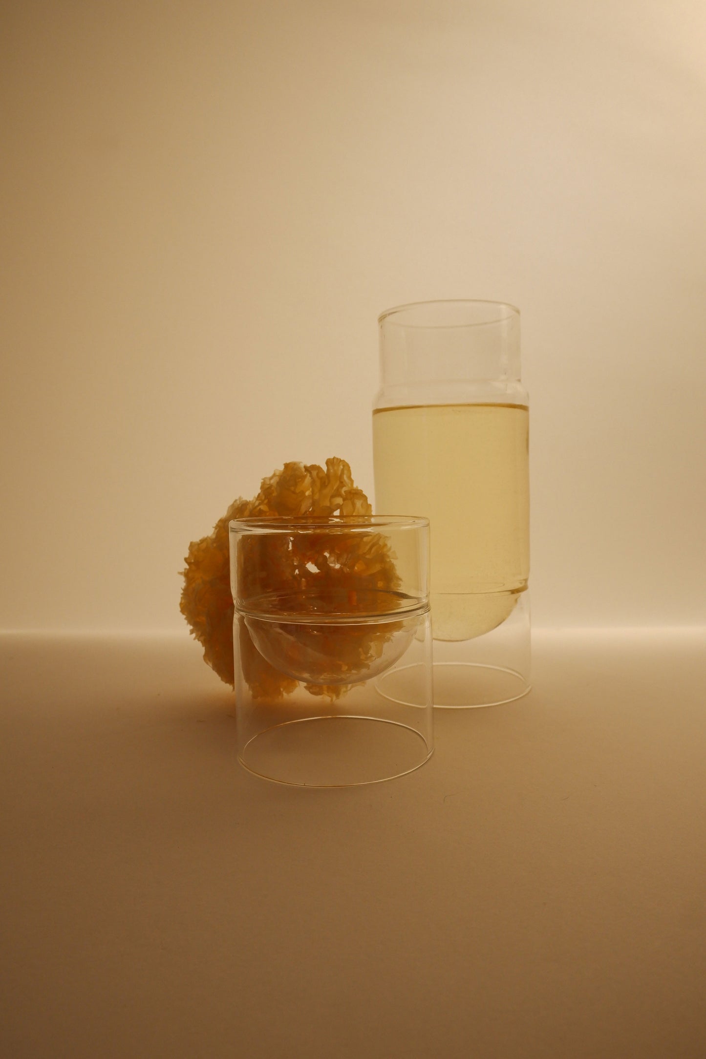 Two glass containers with a yellowish substance on a beige background
