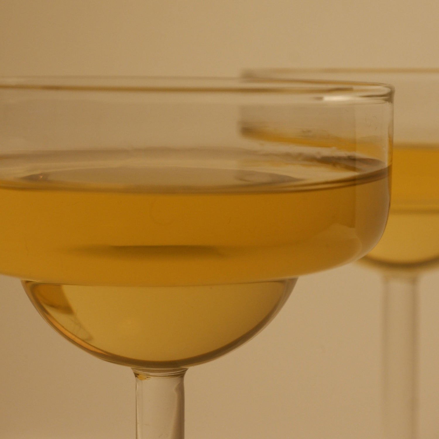 Two glasses of white wine against a beige background