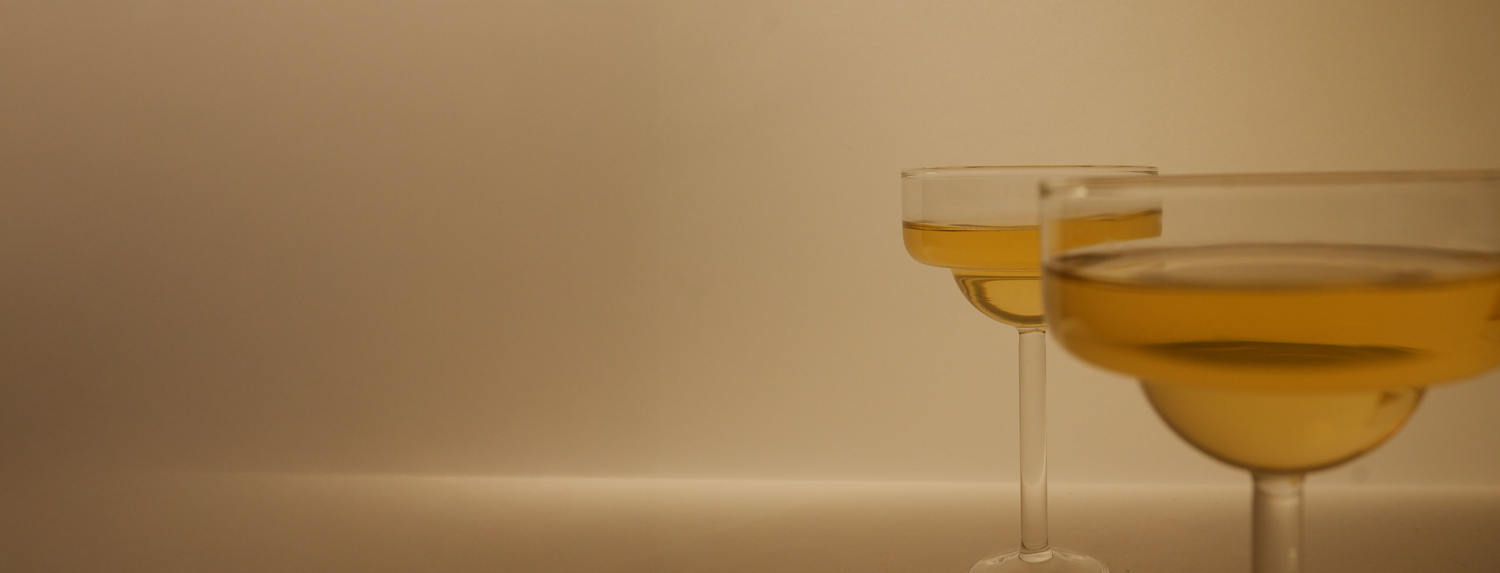 Two glasses of yellow liquid on a beige background