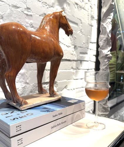 Wooden horse figurine on books with a glass of wine in the background