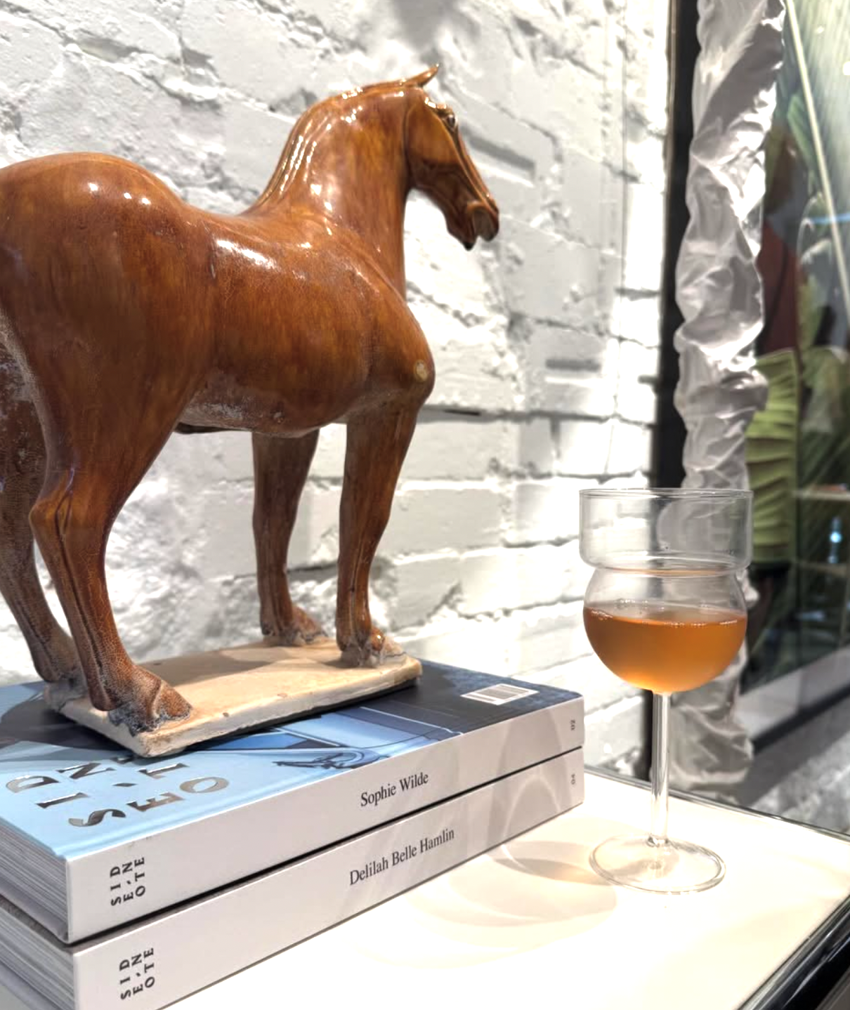 Wooden horse figurine on books with a glass of wine in the background