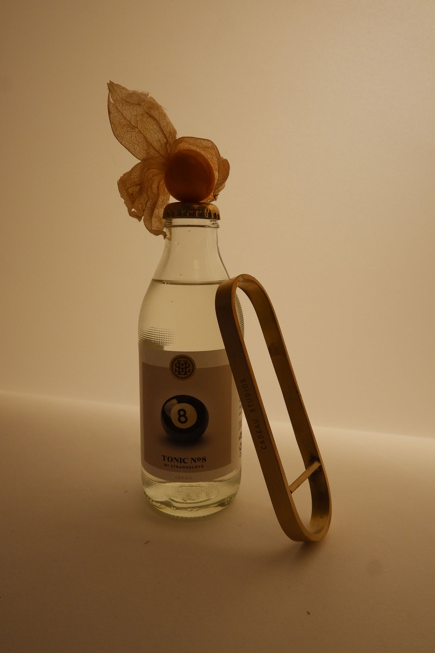 Clear bottle with a dried flower on a beige background