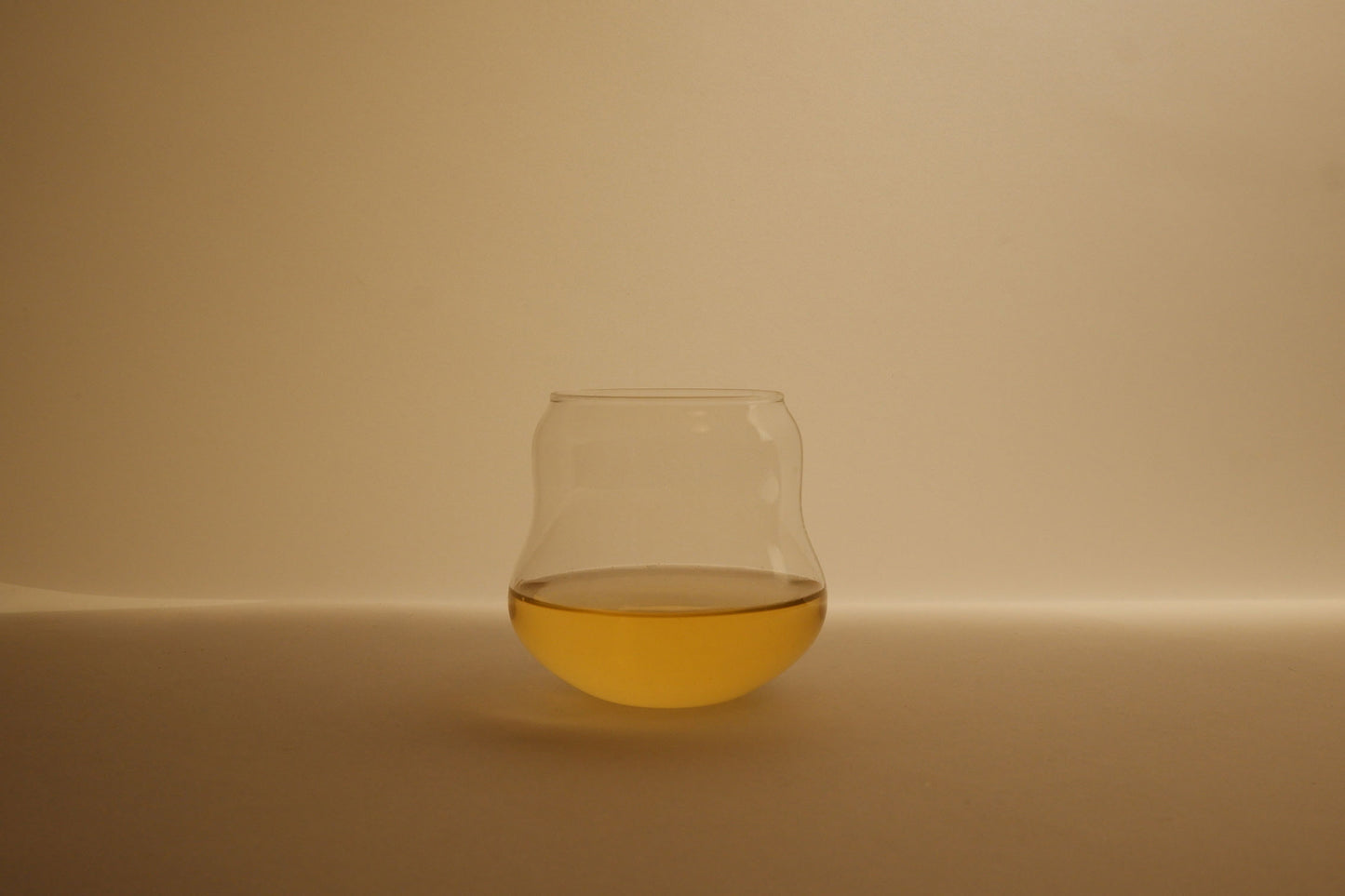 Cin Cin curvy tumbler glass with liquid on a beige background