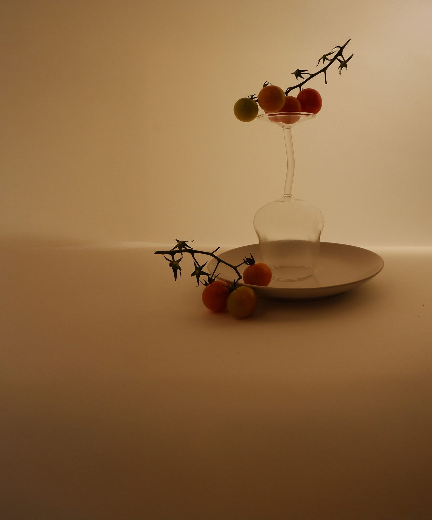 Clear glass vase with red and green fruits on a white plate against a beige background
